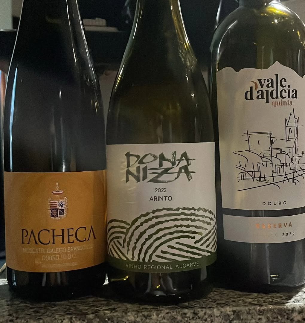 Três garrafas de vinho português, Pacheca e Vale d'Aldeia do Douro e Dona Niza Arinto do Algarve, sobre um balcão de pedra